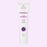 A white squeeze tube of Doublebase Dry Skin Emollient 100g with purple text and a purple circular seal, centered on a light lavender background.