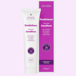 Doublebase Dry Skin Emollient 100g tube next to its purple and white packaging box, set against a solid pale lavender background.