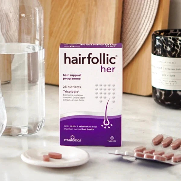 vitabiotics hairfollic her with some tablets and a water bottle on table