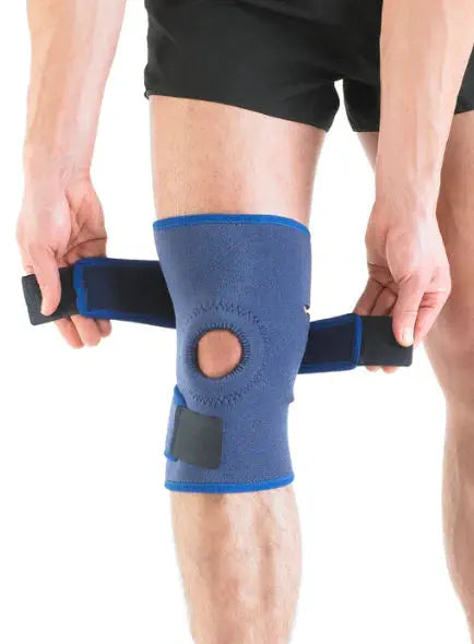 Person applying a knee support bandage with velcro straps on the knee.