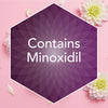 A purple hexagonal badge on a pink background with white flowers and petals, containing the text 'Contains Minoxidil' in white.