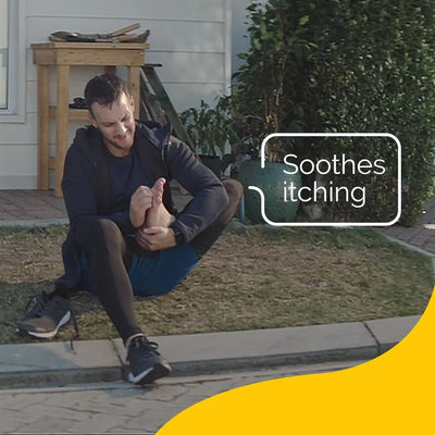 A man sits on grass, holding his foot, with "Soothes itching" text.