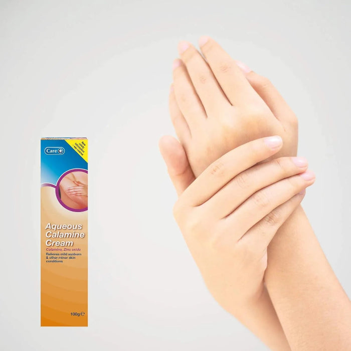 Box of Aqueous Calamine Cream with a hand applying cream to another hand on a light gray background
