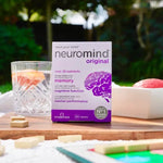 Neuromind Original 30 tablets displayed outdoors with a glass of juice and a wooden game set.