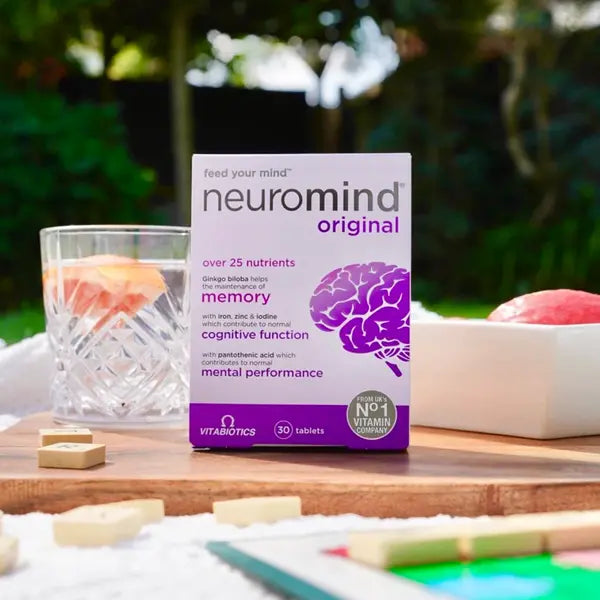 Neuromind Original 30 tablets displayed outdoors with a glass of juice and a wooden game set.