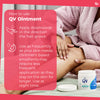 Person applying QV Ointment with usage instructions on a pink background