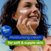Woman applying Nivea moisturizing cream on her face with a blue background